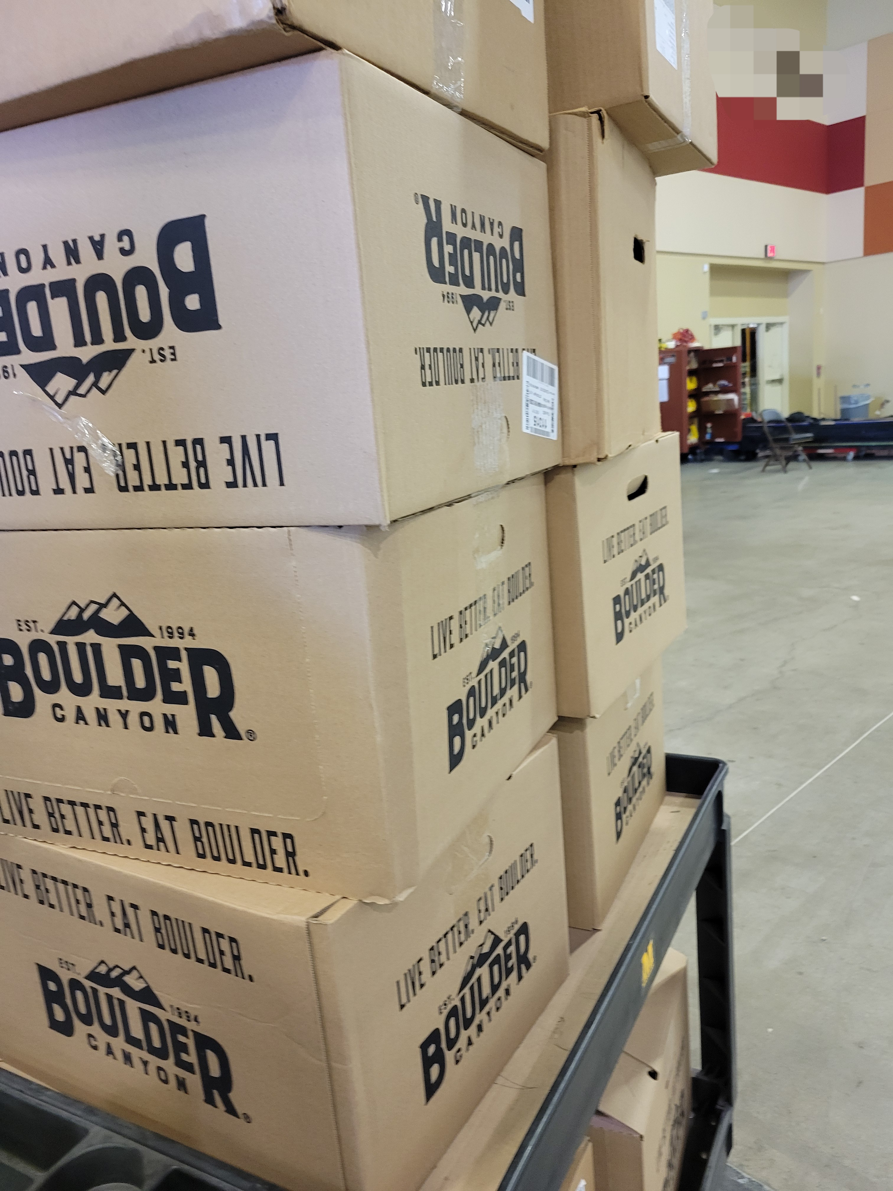 Rows of cardboard boxes of chip stacked on a shelf cart.